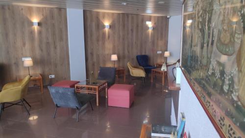 a waiting area with chairs and tables in a room at Hotel Alnacir in Faro