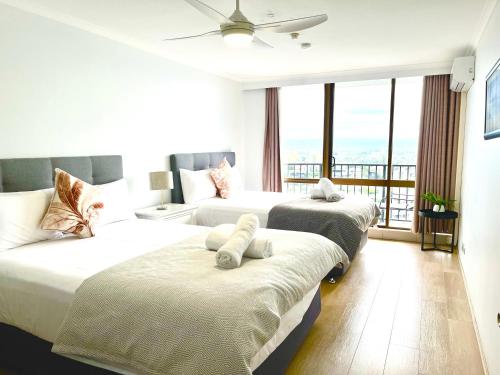 a hotel room with three beds and a large window at Silverton Apartment Resort Surfers Paradise in Gold Coast
