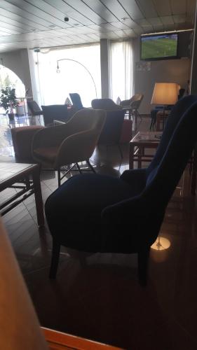a room with chairs and tables and a television at Hotel Alnacir in Faro
