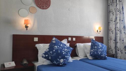 a bedroom with a bed with blue and white pillows at Hotel Alnacir in Faro