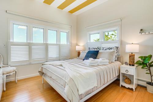 a white bedroom with a large bed with windows at Elegant Gloucester Beach Getaway with Ocean Views! in Gloucester