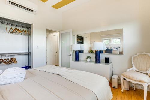 a white bedroom with a bed and a chair at Elegant Gloucester Beach Getaway with Ocean Views! in Gloucester