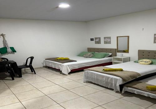Habitación con 2 camas, silla y espejo. en Residencial Margarida APART 5 en Presidente Figueiredo