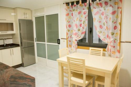 a kitchen with a table and chairs and a kitchen with a refrigerator at Alojamiento YASA in Sarria