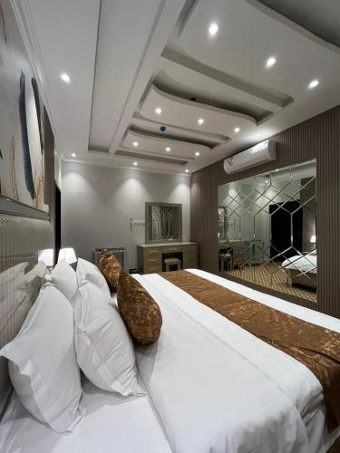 1 dormitorio con 1 cama grande con almohadas blancas en ALSEEB VIEW Serviced Hotel Suites, en Raʼs al Khafjī