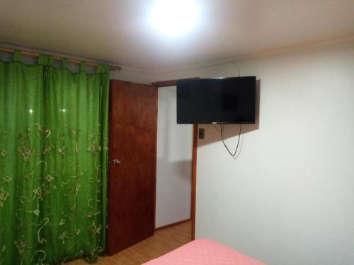 um quarto com uma cortina verde e uma televisão de ecrã plano em Cabaña florencia em Coquimbo