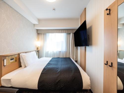 a hotel room with a bed and a television at APA Hotel Osaka Kadomashi Ekimae in Kadoma