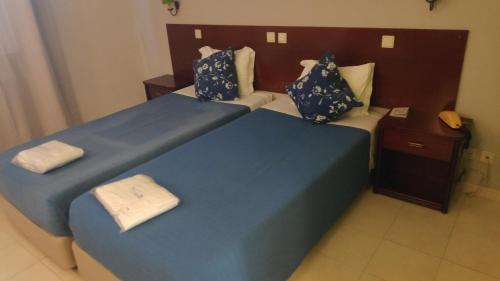 a bedroom with two beds with blue sheets and pillows at Hotel Alnacir in Faro