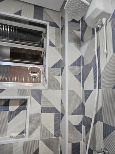 uma casa de banho com chuveiro e azulejos geométricos na parede em Apartamentos na Praia do Gonzaga em Santos