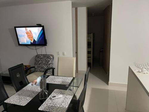 a dining room with a table and a tv on the wall at peña azul la morada Sánchez in Ricaurte