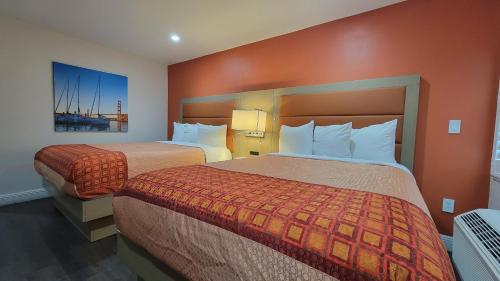 Habitación de hotel con 2 camas y paredes de color naranja en Presidio Parkway Inn en San Francisco