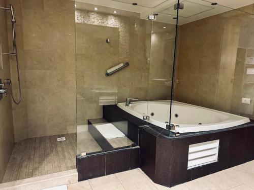 y baño con bañera y ducha acristalada. en Hotel Mirage - Centro Histórico de Querétaro, en Querétaro
