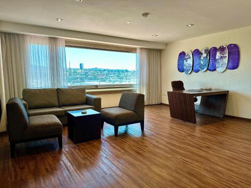 a living room with a couch and chairs and a window at Hotel Mirage - Centro Histórico de Querétaro in Querétaro
