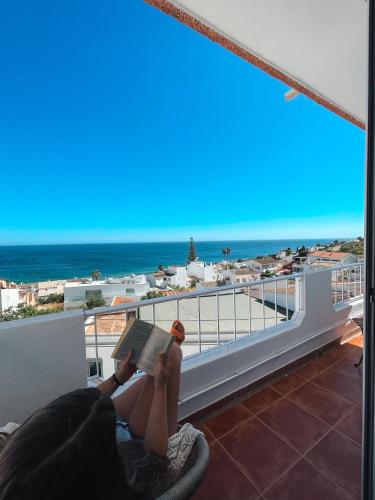 a woman laying on a balcony reading a book at Casa Amar- Vista panorâmica in Luz