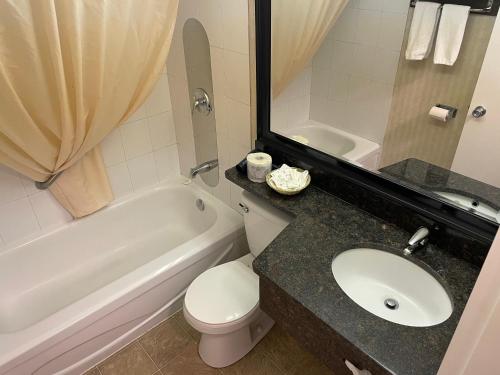 a bathroom with a toilet and a sink and a mirror at Almac Hotel in Lac La Biche