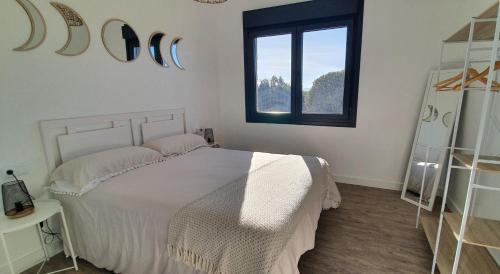 a bedroom with a white bed and a window at Apartamento A Cachola in Cangas de Morrazo