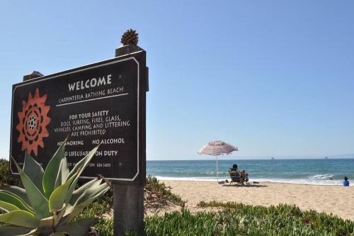 a sign on the beach with people sitting under an umbrella at Carpinteria Beach Studio Condo in Carpinteria