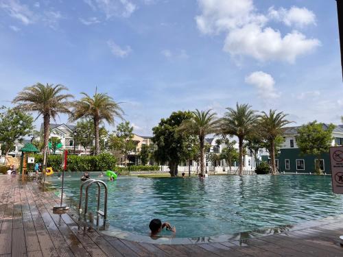 a child swimming in a swimming pool with palm trees at Chau's House Novaworld Phan Thiet in Bình Tú