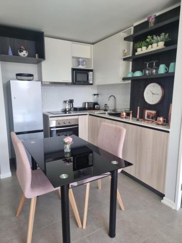 a kitchen with a black table and two pink chairs at A pasos de la UDEC y centro in Concepción