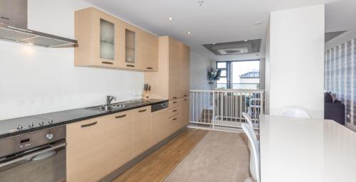 a kitchen with white walls and wooden cabinets at Seaside at Eleven Mt Maunganui in Mount Maunganui