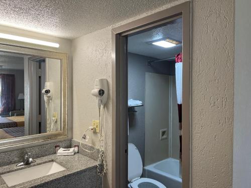 y baño con lavabo, aseo y espejo. en American Inn Columbia en Columbia