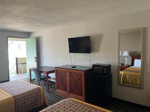 a hotel room with a bedroom with two beds and a television at American Inn Columbia in Columbia