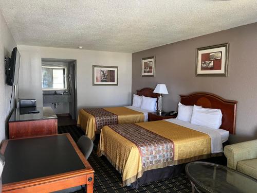 a hotel room with two beds and a table at American Inn Columbia in Columbia