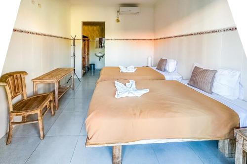 a bedroom with two beds and a desk and a table at Sanata Yoga Guesthouse in Canggu