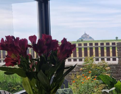 un vaso con fiori viola seduto in una finestra di Vue sur le Mont St Michel, Grand confort et bien équipé a Huisnes-sur-Mer