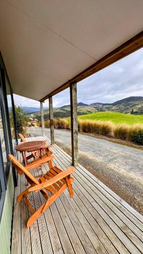 a porch with two chairs and a table on it at Mohua Park - Catlins Eco Accommodation in Owaka