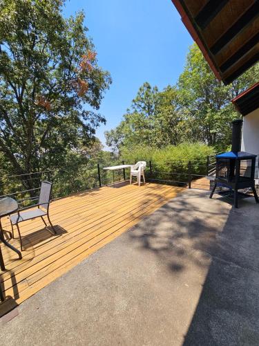 a wooden deck with a table and chairs on it at Casa Alrededor de un Pino in Mazamitla
