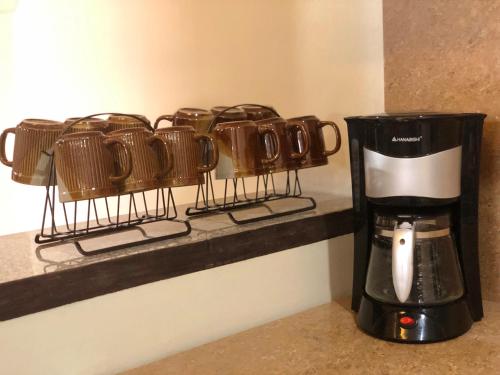 a coffeemaker on a shelf with a row of coffee cups at Prime Location, Spacious & Modern 4BR City Townhouse in Cagayan de Oro