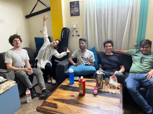un grupo de hombres sentados en una sala de estar en HOSHTEL99 - Stay, Cowork and Cafe - A Backpackers Hostel, en Pune
