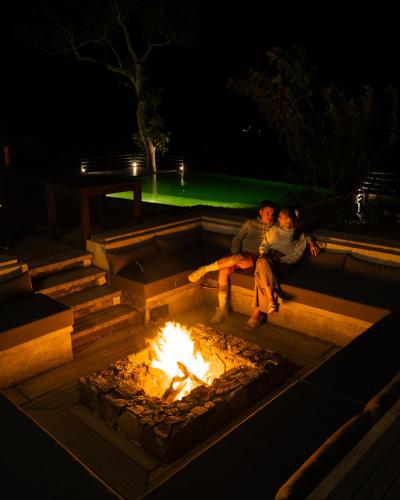 two people sitting around a fire pit at night at Villa Lé Maas Tota by 98 Acres in Koslanda