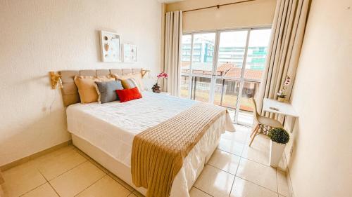 1 dormitorio con cama y ventana grande en Pé na Areia Praia do forte Cama Queen Wifi Netflix en Cabo Frío