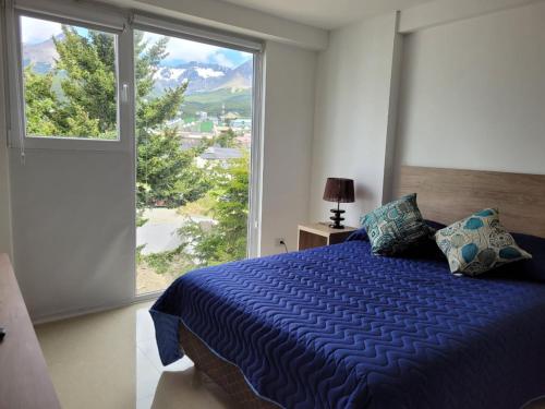 1 dormitorio con cama azul y ventana grande en Gente del Sur - Marinas Towers en Ushuaia