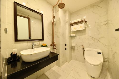 a bathroom with a sink and a toilet and a mirror at Kingdom Hotel Hanoi in Hanoi