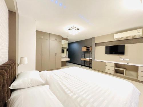 a bedroom with a large white bed and a television at The Wellbeing House in Hat Yai