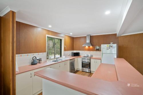 a kitchen with white cabinets and a pink counter top at A Turtle House by Discover Stradbroke in Point Lookout