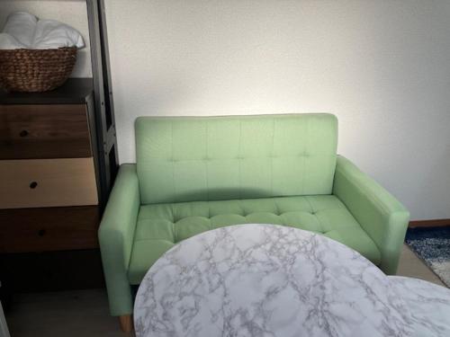 a green couch in a living room with a table at Feliz Kumamoto in Kumamoto