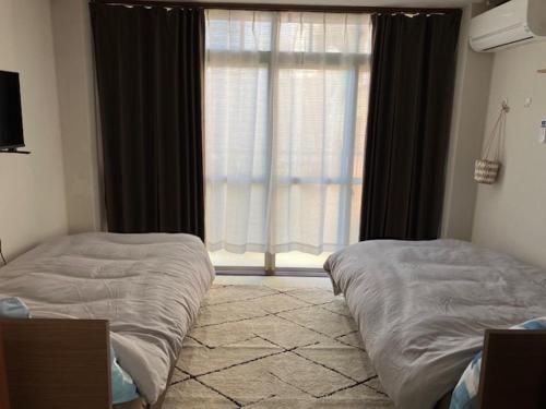a bedroom with two beds and a large window at Feliz Kumamoto in Kumamoto