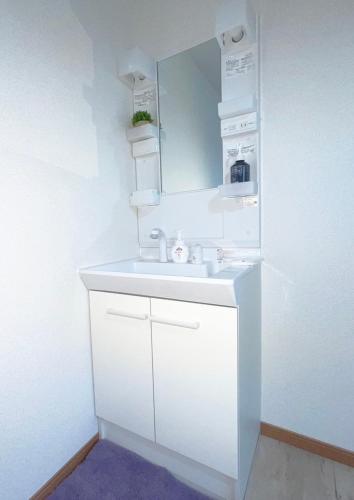 a white bathroom with a sink and a mirror at Feliz Kumamoto in Kumamoto