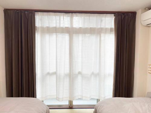 a bedroom with a large window with curtains at Feliz Kumamoto in Kumamoto