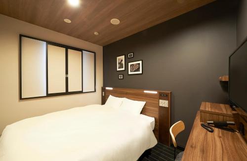 1 dormitorio con 1 cama blanca y TV en Sotetsu Fresa Inn Nihombashi Kayabacho en Tokio