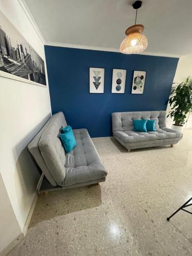 una sala de estar con 2 sofás y una pared azul en Cabrero Beach 1212, en Cartagena de Indias