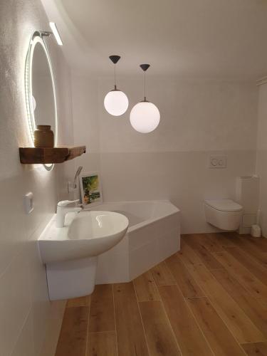 a white bathroom with a sink and a toilet at Ferienhaus Hummel-Nest in Laußnitz