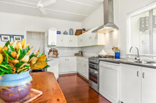 a kitchen with white cabinets and a table with a vase of flowers at Tamarind Street Cottage. Maleny, Queensland in Maleny