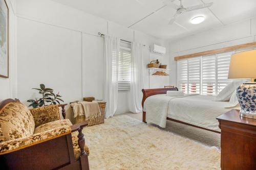 a bedroom with a bed and a chair and a window at Tamarind Street Cottage. Maleny, Queensland in Maleny