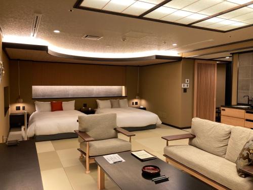 諏訪市にある信州上諏訪温泉 浜の湯のベッド2台とリビングルームが備わるホテルルームです。