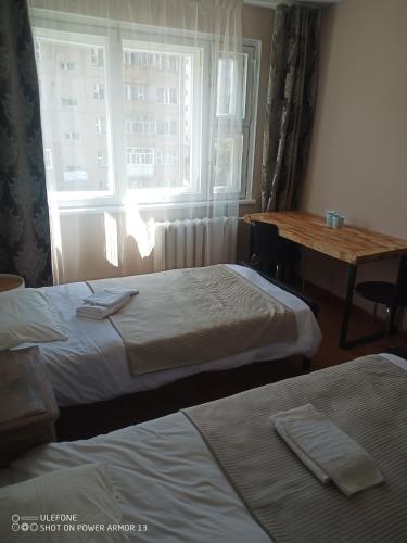 a room with two beds and a table and a window at tsogoo's geust house in Ulaanbaatar